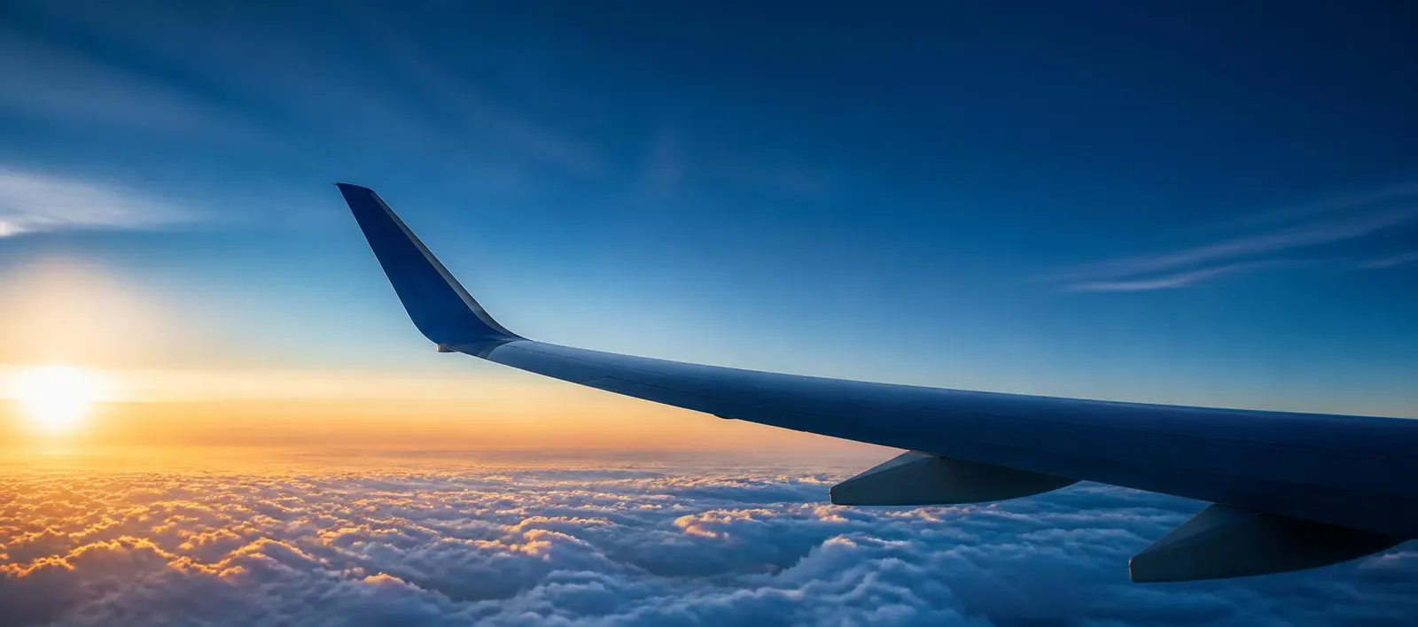 Aircraft wing above the clouds at sunrise